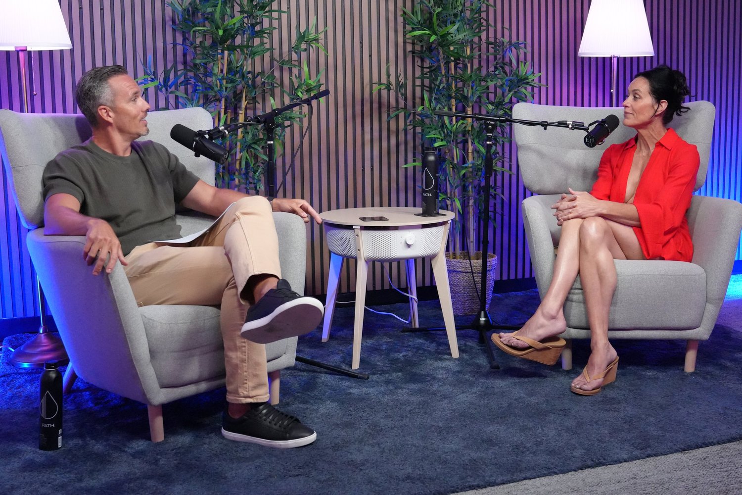 Two people in armchairs in a podcast studio