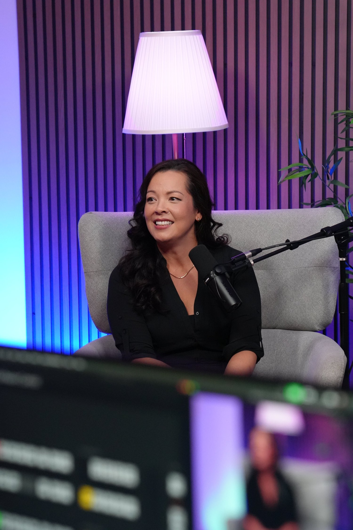 Woman on a gray chair with microphone and purple-blue background