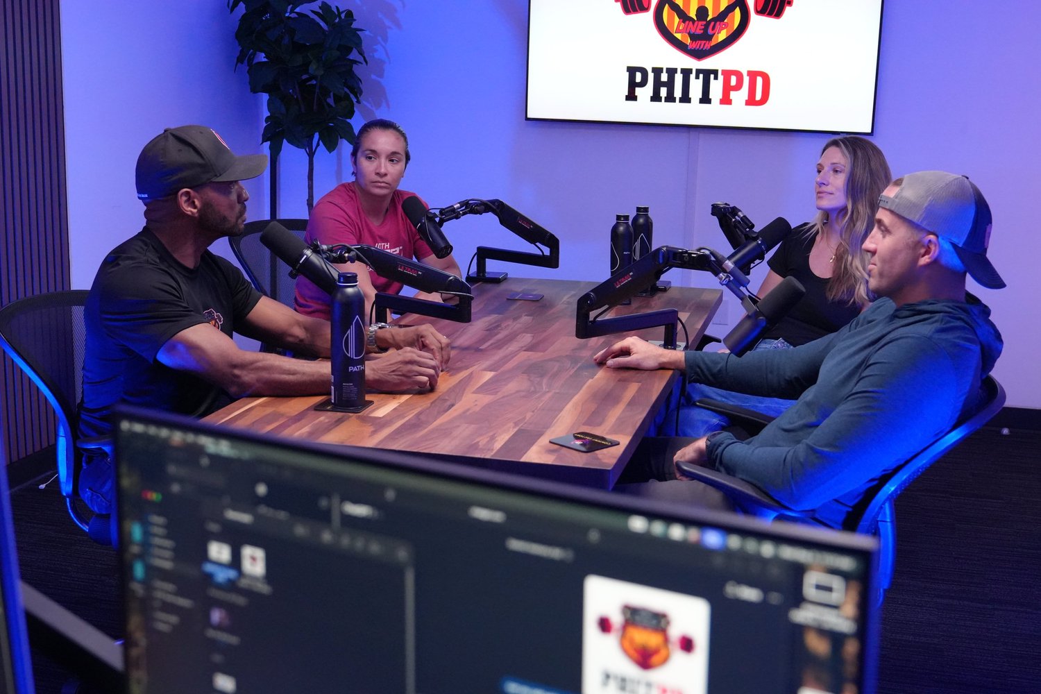 Four people at a wooden table with microphones