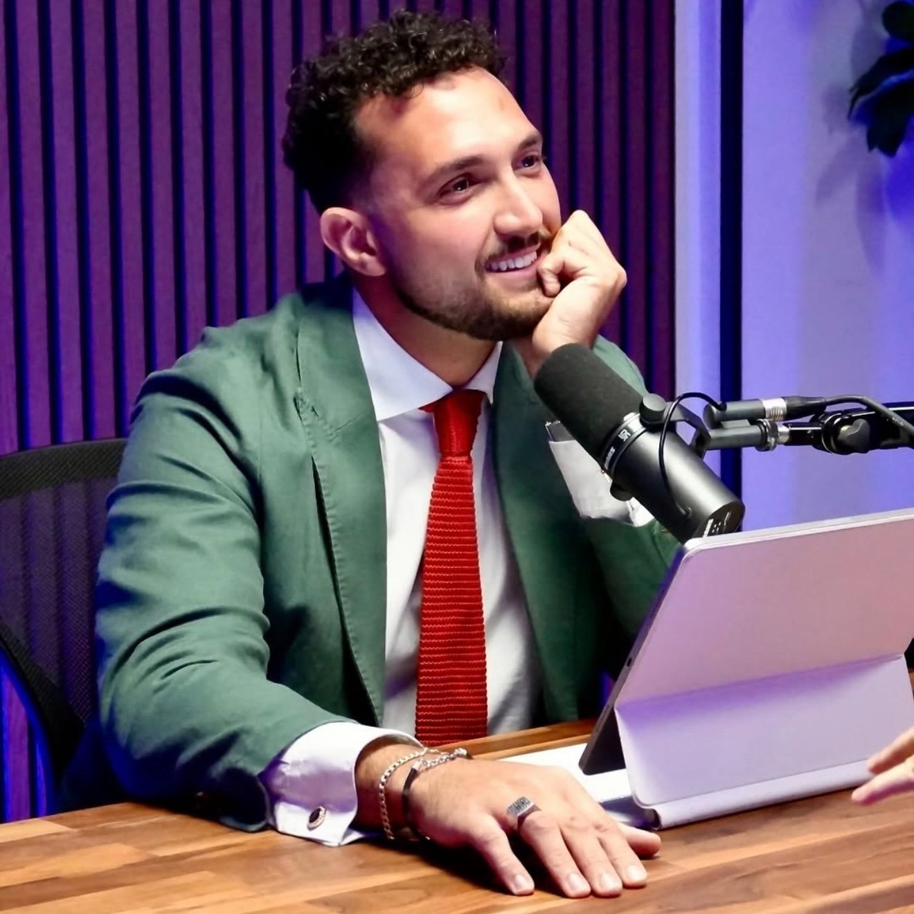 Man at a desk with tablet and microphone in a recording studio