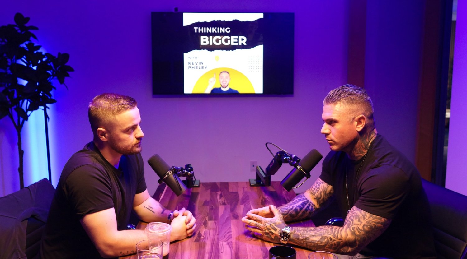 Two men at a wooden table recording a podcast